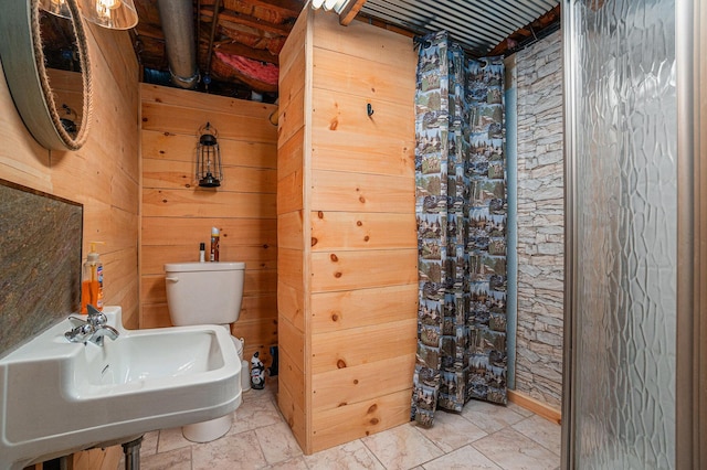 bathroom featuring toilet, sink, and wood walls