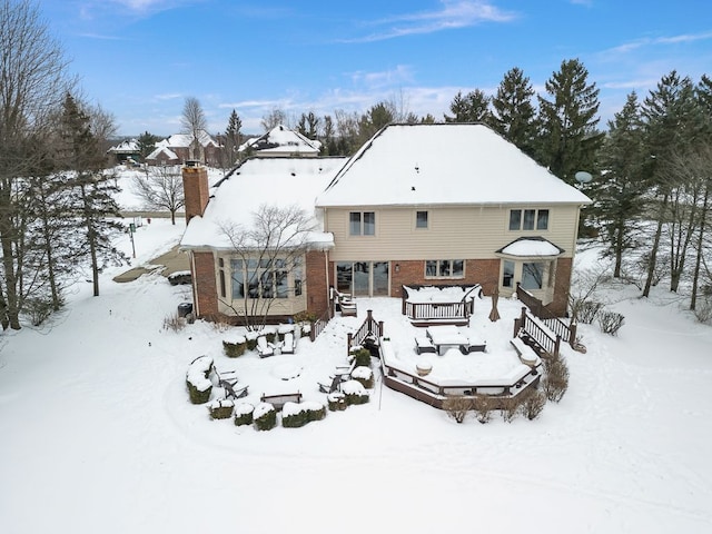 snow covered rear of property featuring brick siding