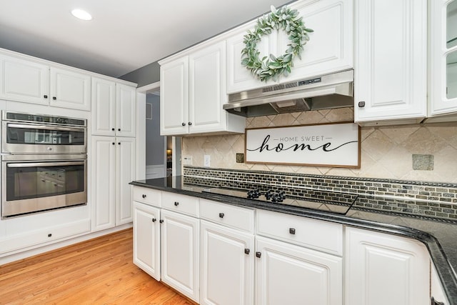 kitchen with double oven, white cabinets, and under cabinet range hood