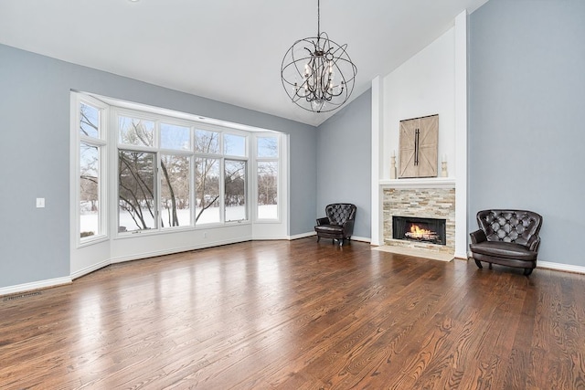 unfurnished room with a chandelier, a stone fireplace, wood finished floors, visible vents, and vaulted ceiling