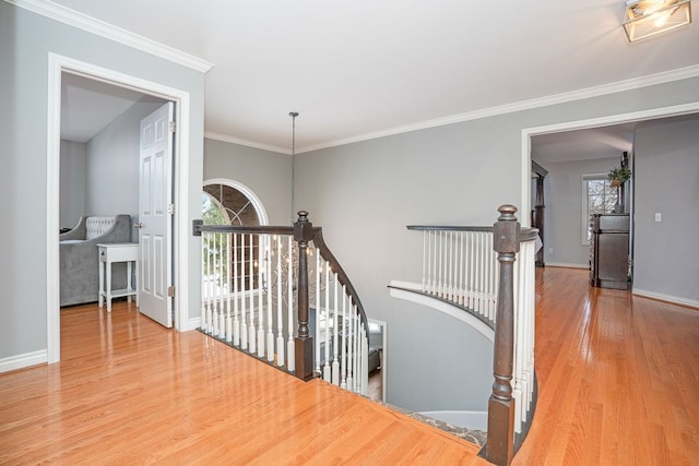 hallway featuring baseboards, crown molding, an upstairs landing, and wood finished floors