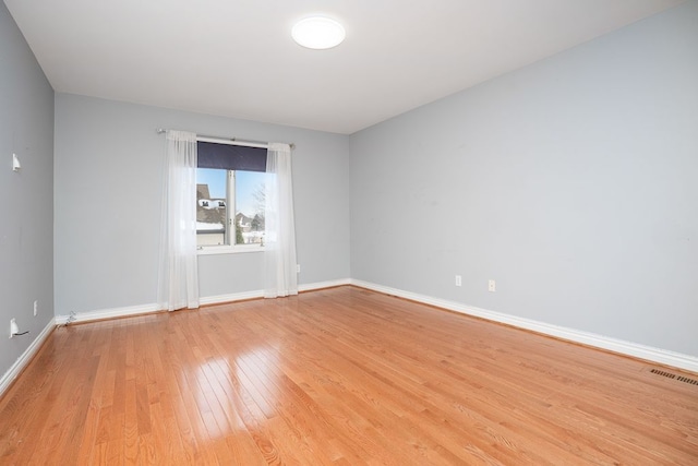 unfurnished room with baseboards, visible vents, and light wood-style floors