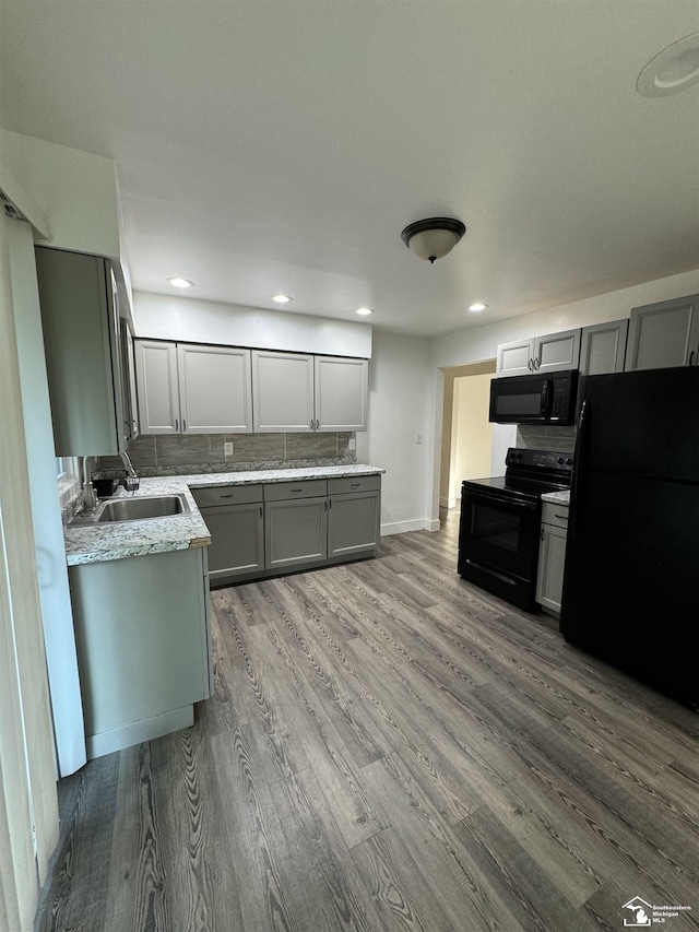 kitchen with gray cabinets, tasteful backsplash, wood-type flooring, sink, and black appliances