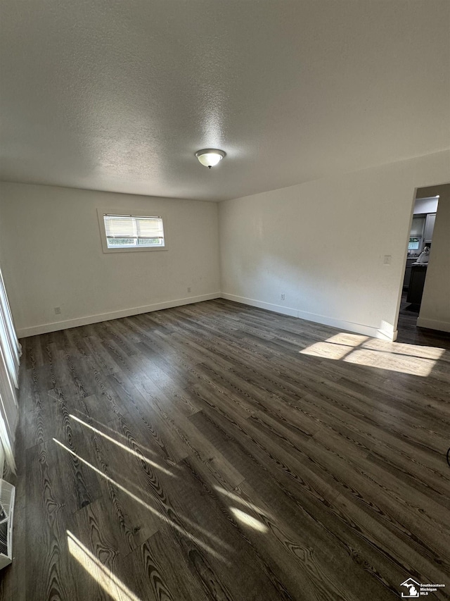 empty room with dark hardwood / wood-style floors and a textured ceiling