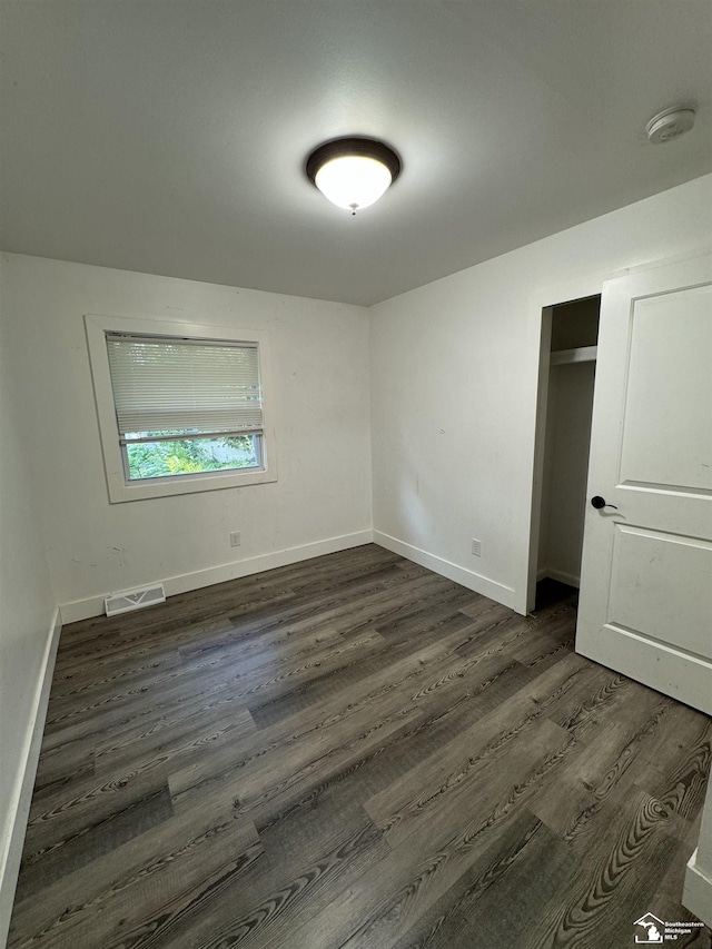 unfurnished bedroom featuring dark hardwood / wood-style floors and a closet