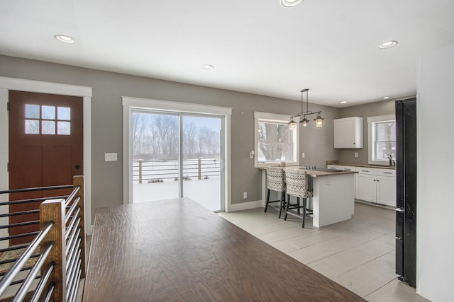 kitchen with white cabinetry, a center island, a breakfast bar, and pendant lighting