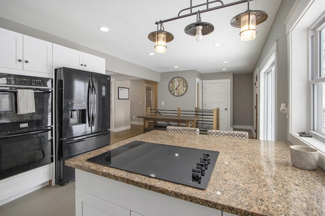 kitchen featuring light stone counters, hanging light fixtures, white cabinetry, and black appliances