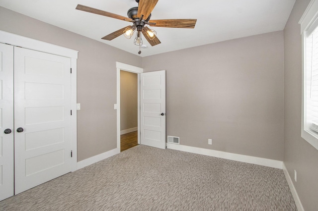 unfurnished bedroom with multiple windows, light carpet, and ceiling fan