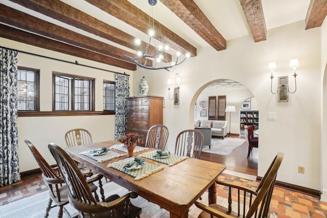 dining area featuring beamed ceiling and a chandelier