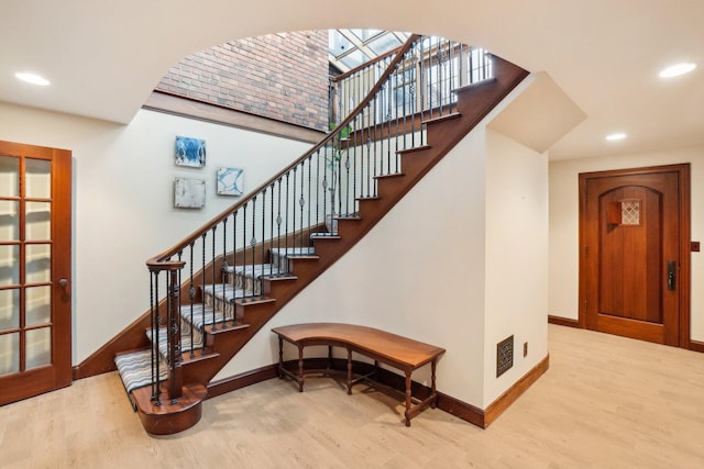 staircase with hardwood / wood-style flooring and a towering ceiling