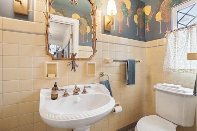 bathroom with toilet, sink, and tile walls