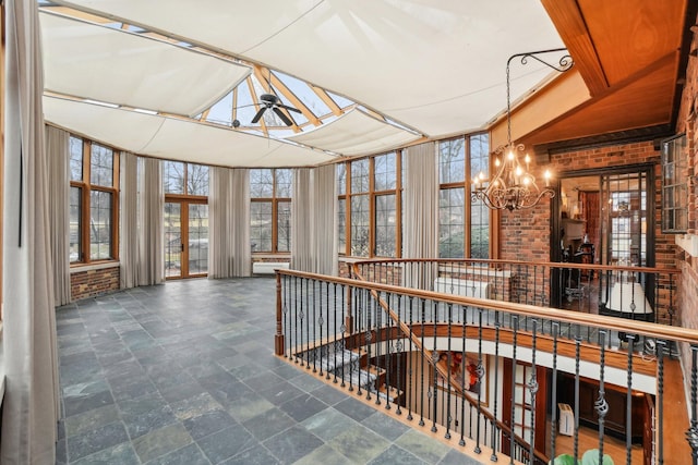 unfurnished sunroom featuring ceiling fan with notable chandelier