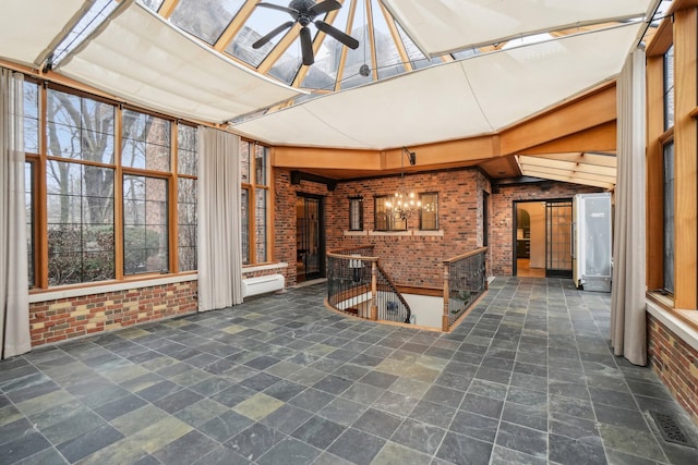 unfurnished sunroom with ceiling fan with notable chandelier