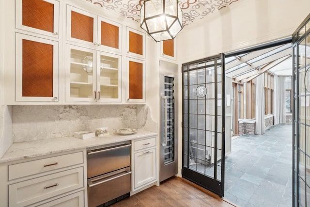 bar featuring pendant lighting, white cabinetry, decorative backsplash, light stone counters, and an inviting chandelier