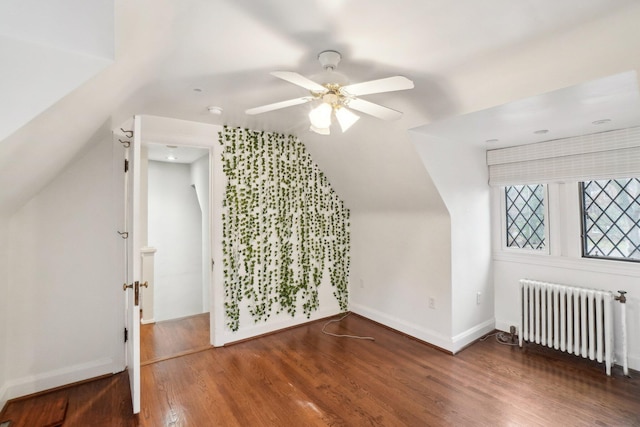 additional living space with dark wood-type flooring, ceiling fan, radiator heating unit, and vaulted ceiling