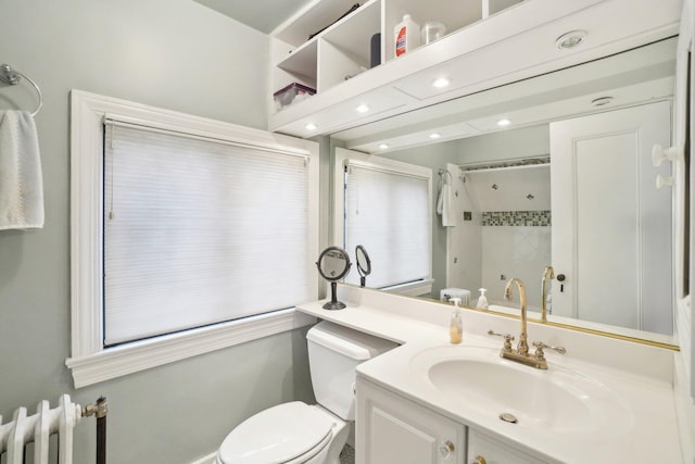 bathroom featuring vanity, radiator heating unit, toilet, and a tile shower