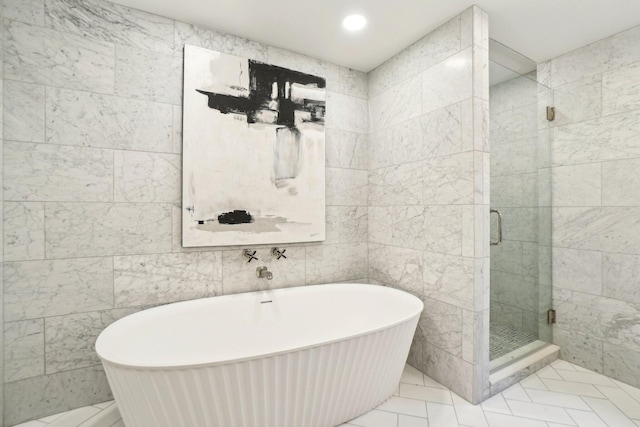 bathroom featuring plus walk in shower and tile walls