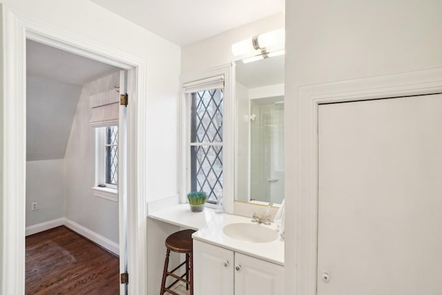 bathroom with vanity, hardwood / wood-style floors, and vaulted ceiling