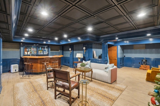 interior space featuring light wood-type flooring, ornamental molding, and bar area