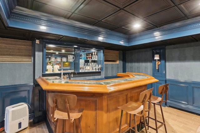 bar with ornamental molding and light wood-type flooring