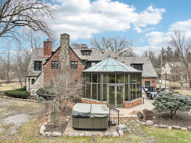 rear view of house with a hot tub, a sunroom, and a patio area