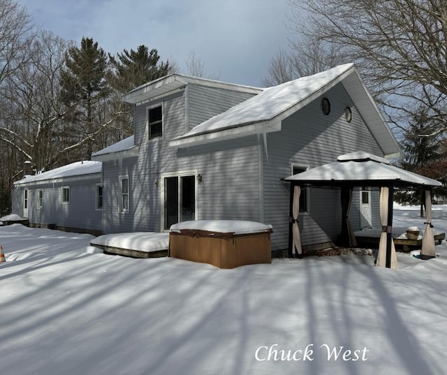 snow covered house featuring a gazebo and a hot tub