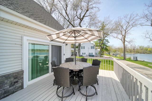deck with a water view and outdoor dining space