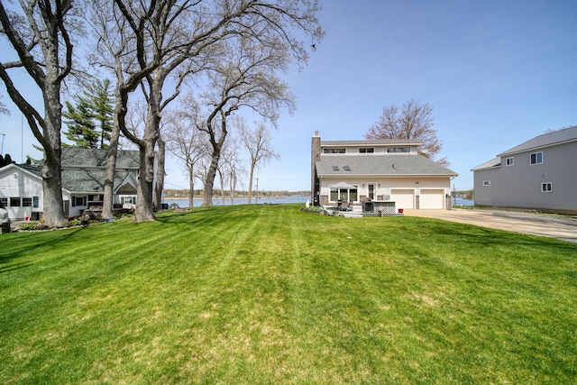 view of yard featuring concrete driveway and a water view