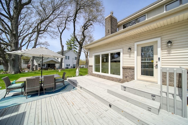 deck featuring outdoor dining area and a yard