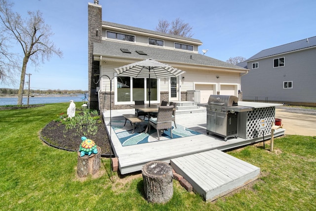 back of house featuring a lawn, a deck with water view, a chimney, and outdoor dining space