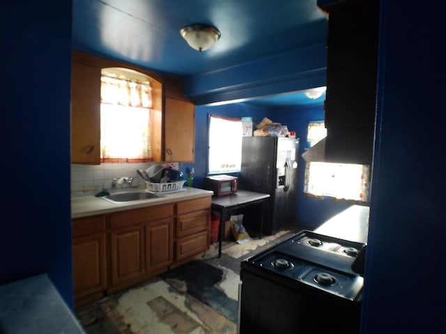 kitchen with sink, fridge with ice dispenser, black range, and decorative backsplash