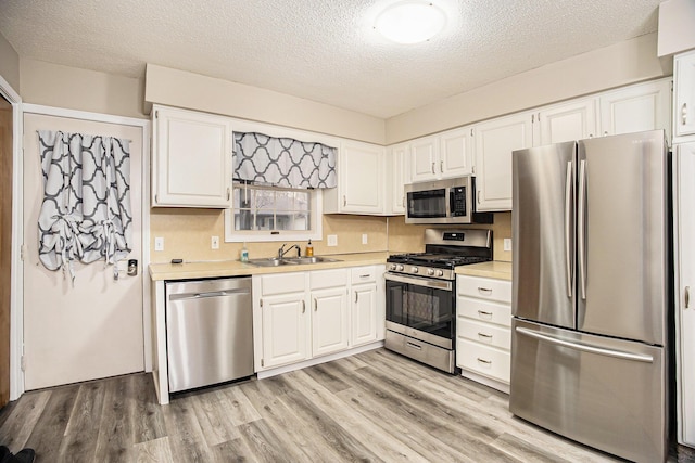 kitchen featuring appliances with stainless steel finishes, white cabinets, and light wood-type flooring