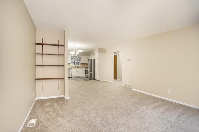 unfurnished living room with light colored carpet and a textured ceiling