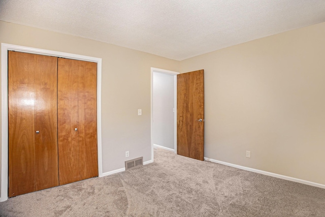 unfurnished bedroom with carpet floors, a closet, and a textured ceiling