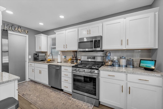 kitchen with white cabinetry, light stone countertops, decorative backsplash, and stainless steel appliances