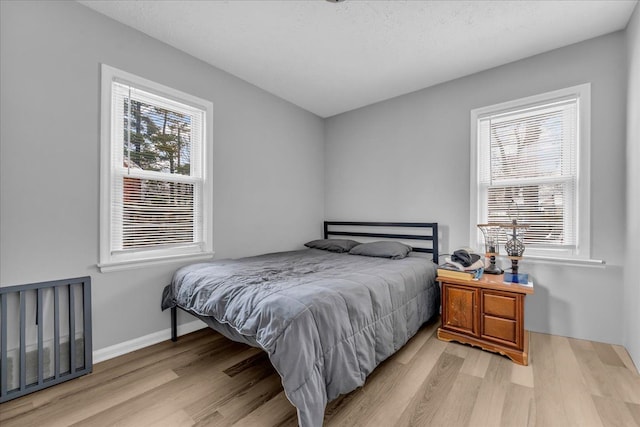 bedroom with multiple windows and light hardwood / wood-style floors