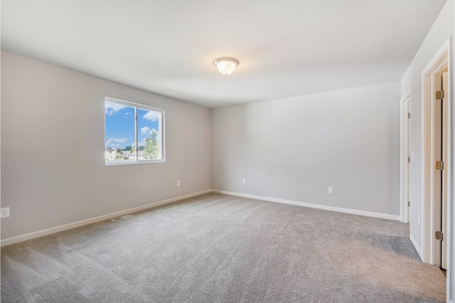 spare room featuring carpet flooring, visible vents, and baseboards