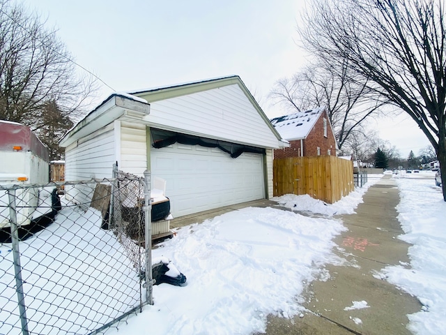 view of snowy exterior featuring a garage and an outbuilding