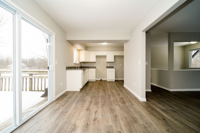 kitchen with white cabinetry, sink, and light hardwood / wood-style flooring