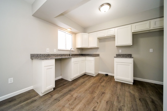 kitchen featuring dark hardwood / wood-style flooring, sink, dark stone countertops, and white cabinets