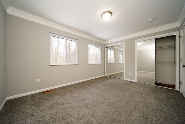 unfurnished bedroom with crown molding, carpet floors, and two closets