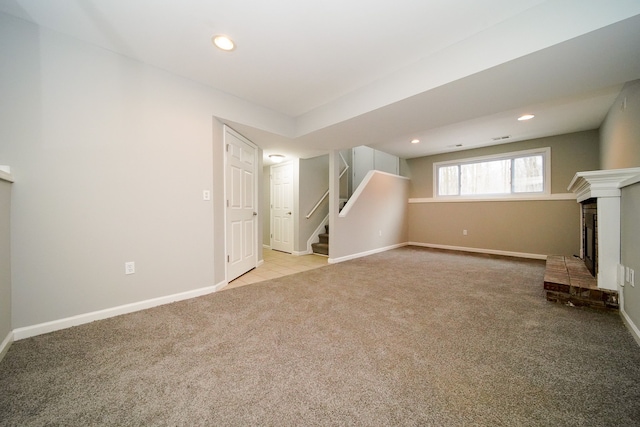 unfurnished living room featuring a brick fireplace and light carpet