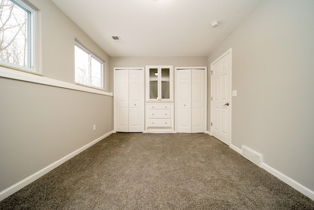 unfurnished bedroom featuring two closets and carpet floors