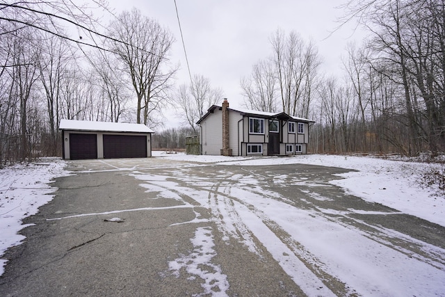 snow covered property featuring a garage and an outdoor structure