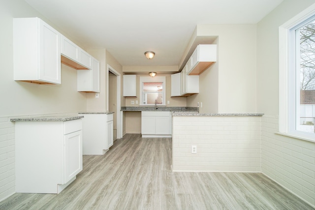 kitchen with light stone countertops, light hardwood / wood-style floors, and white cabinets