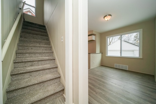 staircase featuring hardwood / wood-style flooring and an AC wall unit