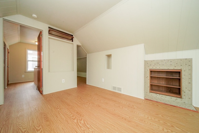 additional living space featuring vaulted ceiling, built in features, and light wood-type flooring