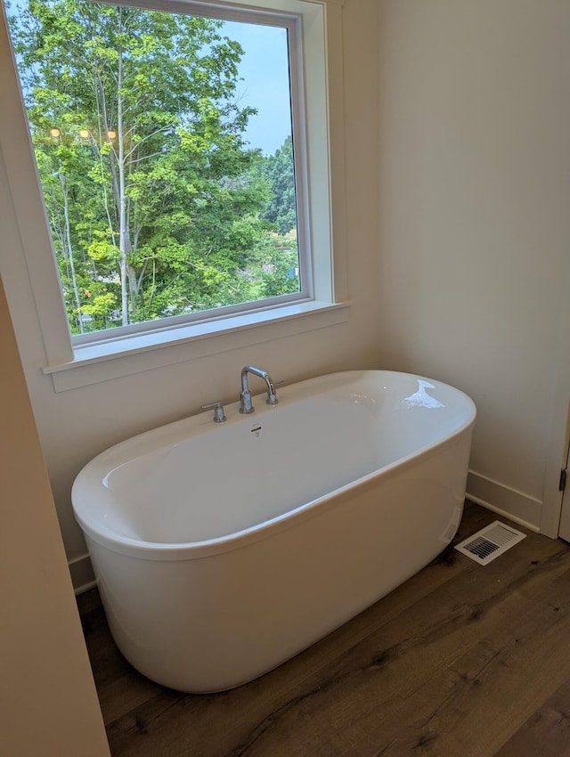 784 Petoskey Stone Dr, Byron Center, MI 49315 - bathroom with wood finished floors, a freestanding bath, and plenty of natural light
