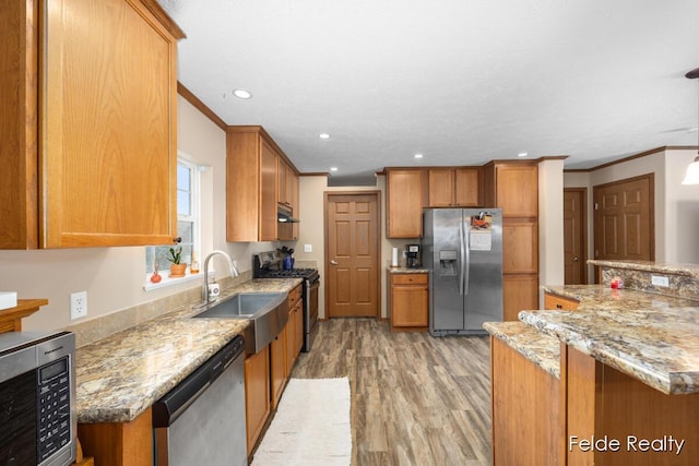 kitchen with light stone counters, sink, light hardwood / wood-style flooring, and appliances with stainless steel finishes