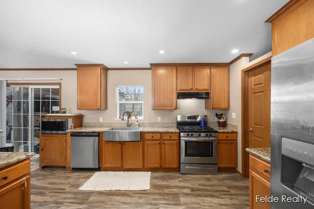 kitchen featuring dark hardwood / wood-style floors, sink, ornamental molding, light stone counters, and stainless steel appliances